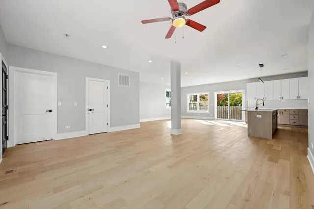 a view of an empty room with a window and kitchen view