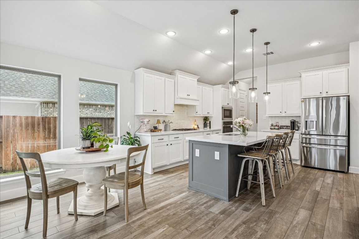 4527 Peloton Road Rosharon, TX 77583 - Photo 14 of 30 a kitchen with a dining table chairs wooden floor cabinets and a window