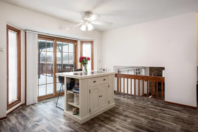 a kitchen with stainless steel appliances a stove a refrigerator a sink a dining table and chairs with wooden floor