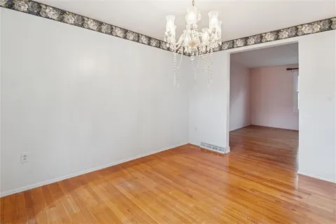 a view of a big room with wooden floor chandelier and closet in it