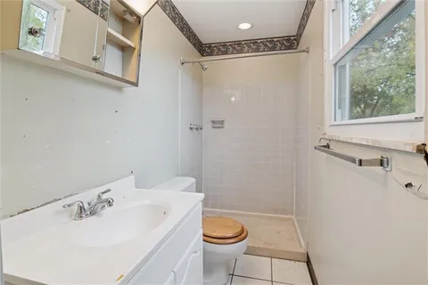 a bathroom with a sink a toilet a window and shower