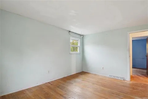 a view of an empty room with wooden floor and closet