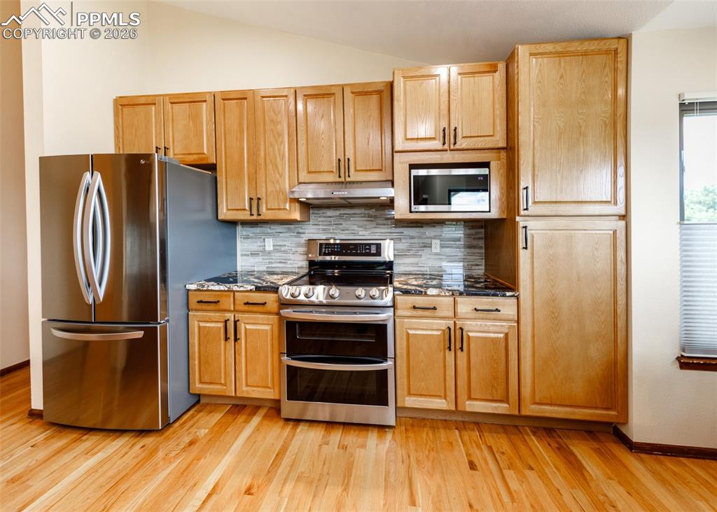 17908 New London Road Monument, CO 80132 - Photo 11 of 41 a kitchen with granite countertop wooden floors stainless steel appliances and cabinets