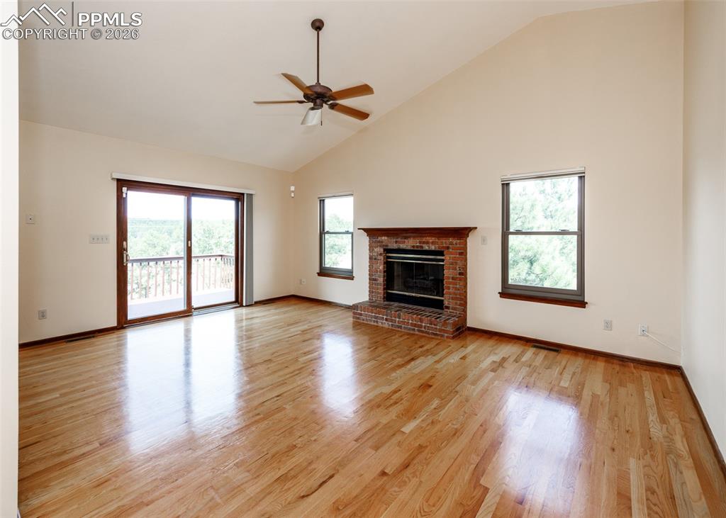 17908 New London Road Monument, CO 80132 - Photo 14 of 41 an empty room with wooden floor fireplace and windows