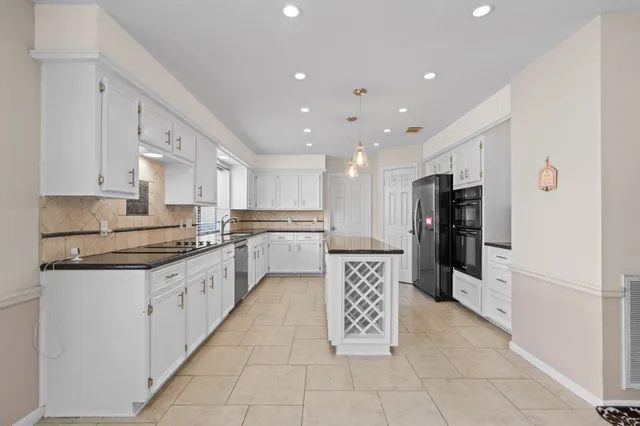 a large kitchen with stainless steel appliances kitchen island granite countertop a refrigerator and a stove top oven