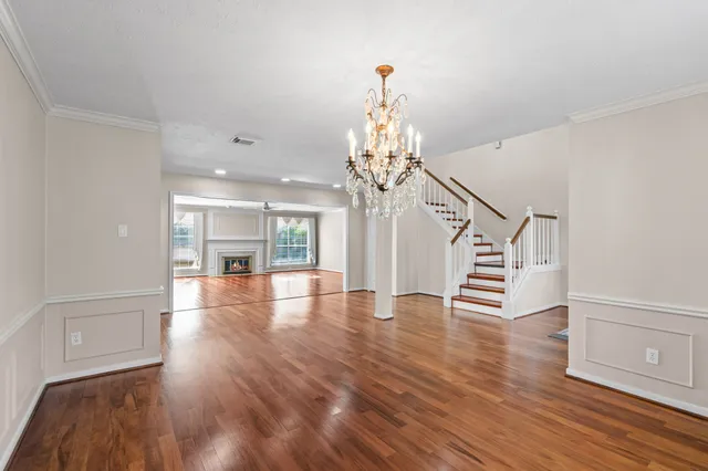 a view of a room with wooden floor chandelier and windows