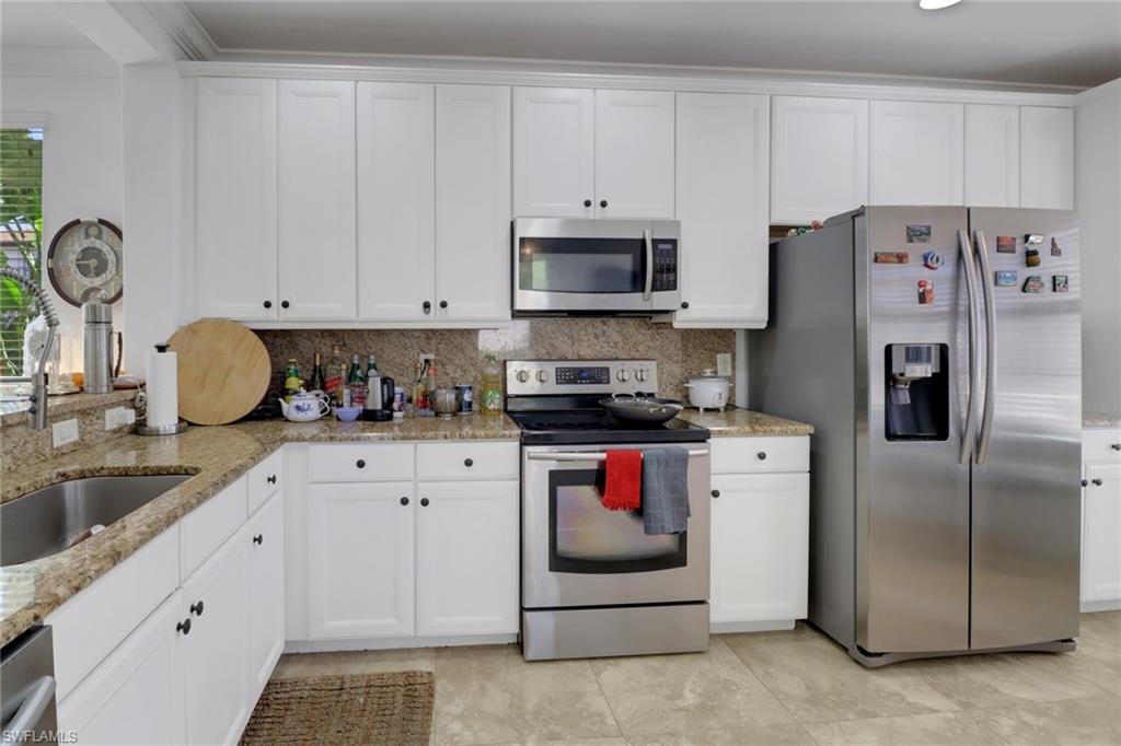 1233 Kendari Terrace Naples, FL 34113 - Photo 4 of 38 a kitchen with stainless steel appliances granite countertop a refrigerator sink stove and white cabinets
