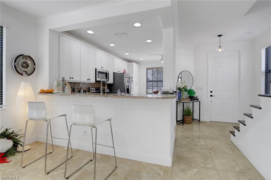 1233 Kendari Terrace Naples, FL 34113 - Photo 7 of 38 a kitchen with stainless steel appliances kitchen island granite countertop a refrigerator and a sink