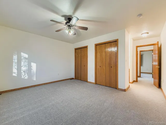 a view of an empty room with chandelier fan