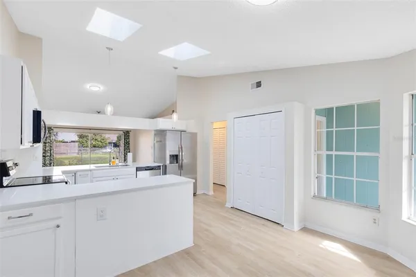 a large white kitchen with a window and kitchen island