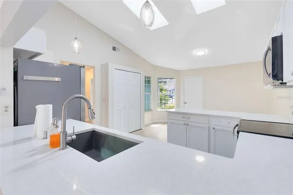a large white kitchen with a sink a counter space and a dining table view