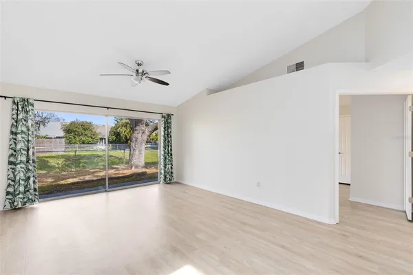 an empty room with wooden floor and windows