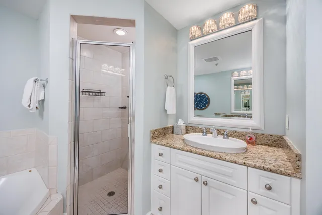 a bathroom with a granite countertop sink two mirror and shower