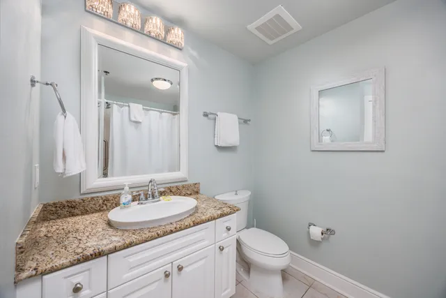a bathroom with a granite countertop sink toilet and mirror