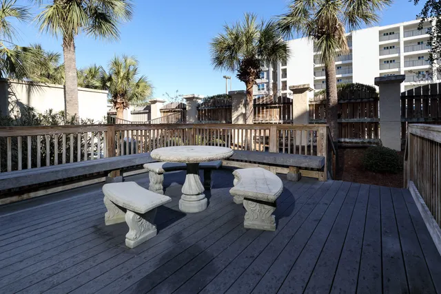 a view of a roof deck with table and chairs couches and a barbeque with wooden floor and fence
