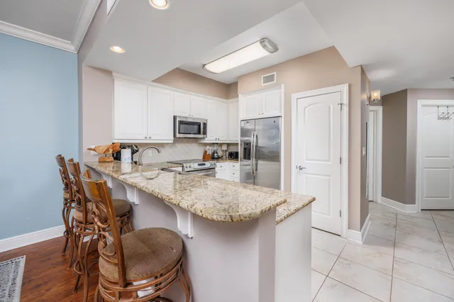 a kitchen with stainless steel appliances granite countertop a table chairs sink refrigerator and microwave