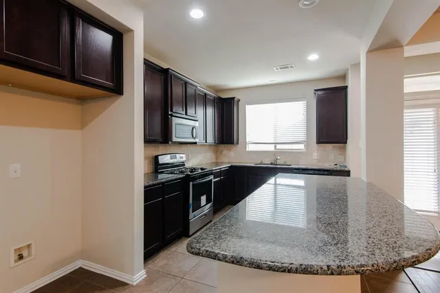 a kitchen with stainless steel appliances granite countertop a stove a sink and a microwave