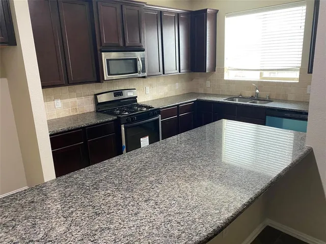 a kitchen with granite countertop wooden cabinets and a stove top oven