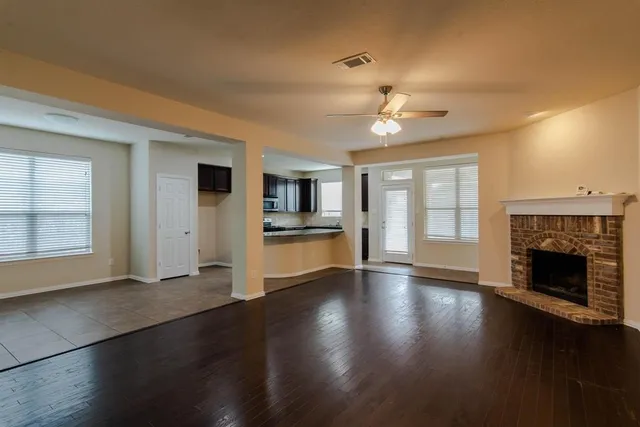 an empty room with wooden floor fireplace and windows