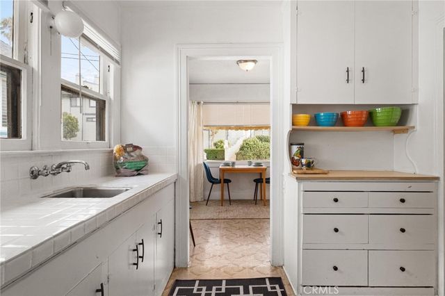a kitchen with a sink and a stove with white cabinets