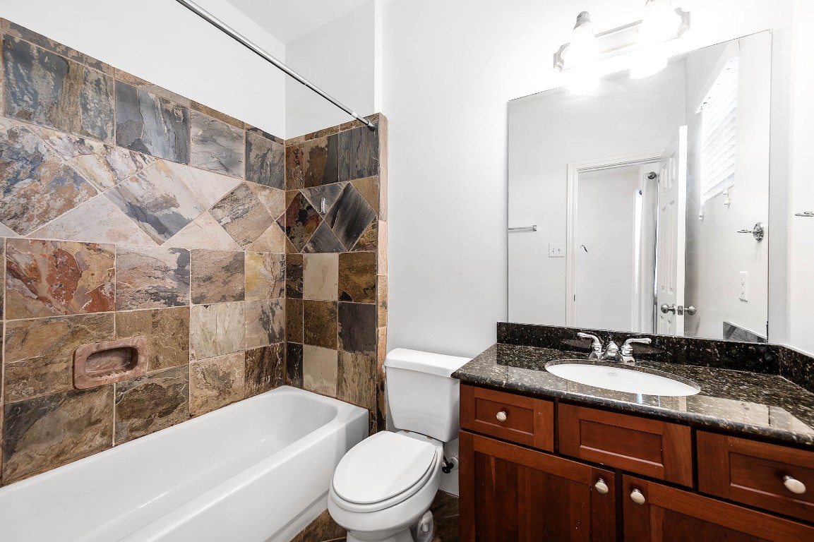 5723 Petty Street Houston, TX 77007 - Photo 26 of 31 a bathroom with a granite countertop bathtub shower sink vanity mirror and toilet