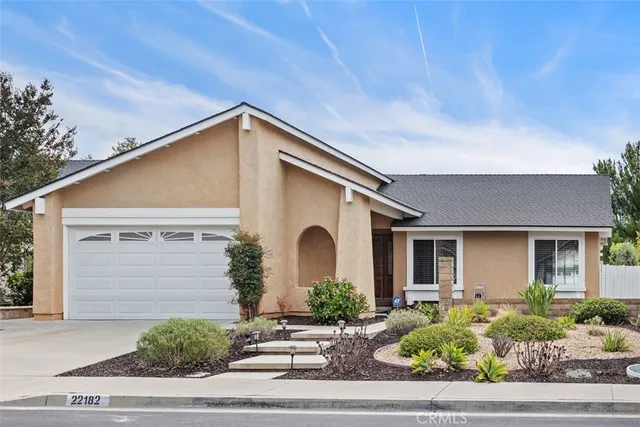 a front view of a house with garage and plants