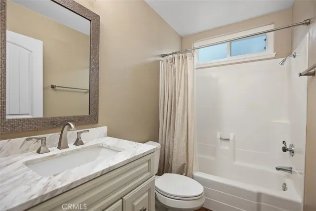a bathroom with a granite countertop sink toilet mirror and shower