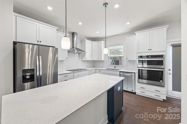 a kitchen with stainless steel appliances a stove a refrigerator a sink and white cabinets