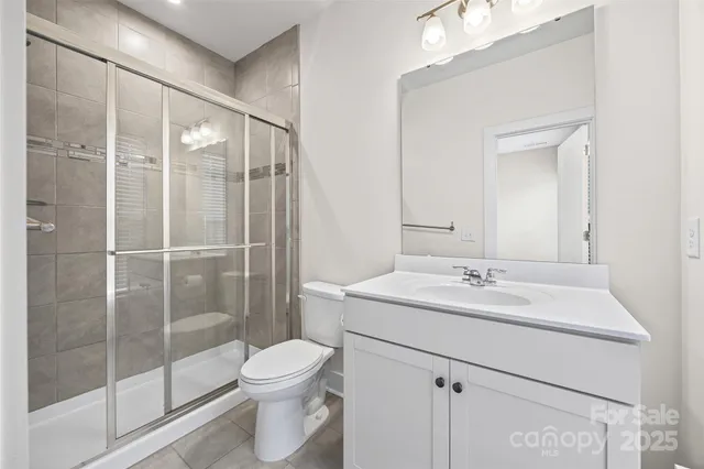 a bathroom with a shower sink vanity mirror and toilet