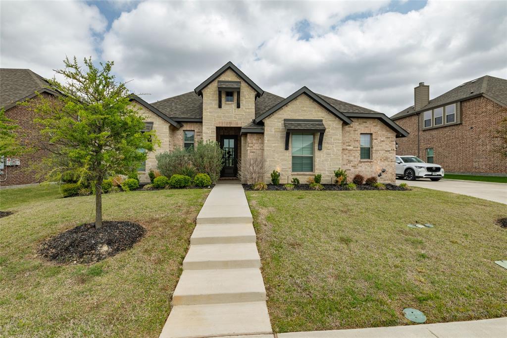View of front of property with a front yard, brick siding, a shingled roof, and stone siding