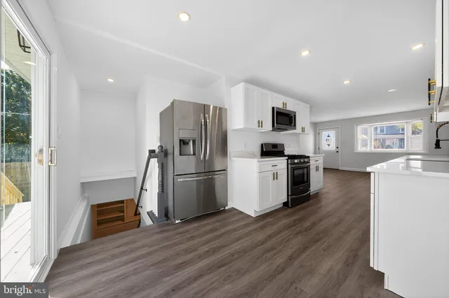 a kitchen with a refrigerator a stove top oven a sink and dishwasher with wooden floor