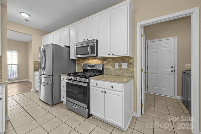 a kitchen with stainless steel appliances granite countertop a refrigerator and a stove top oven