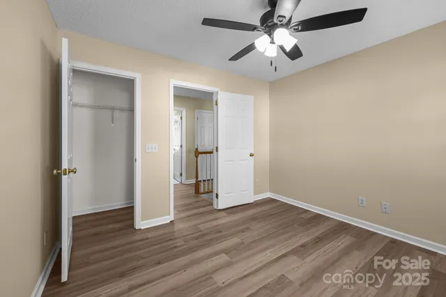 an empty room with wooden floor and a ceiling fan