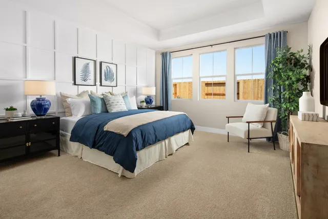 a spacious bedroom with a bed a table and large windows