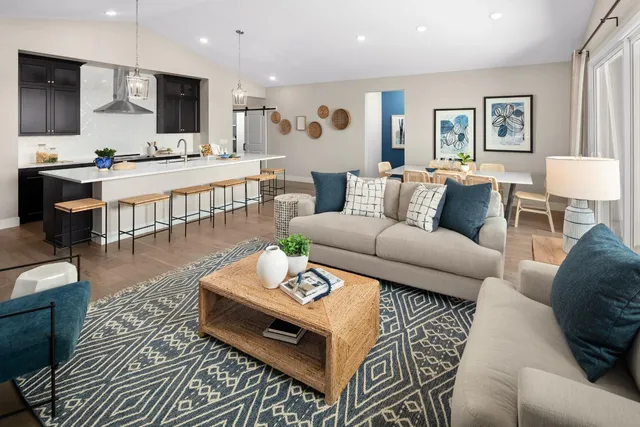 a living room with furniture kitchen view and a wooden floor