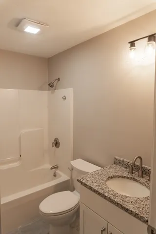 a bathroom with a granite countertop sink toilet and shower