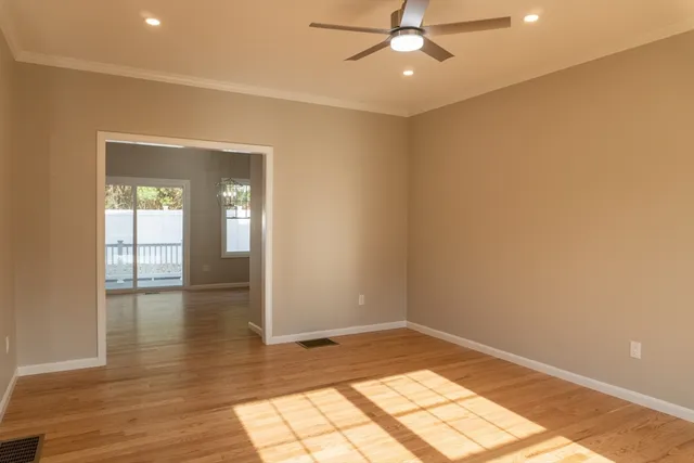 an empty room with wooden floor fan and windows