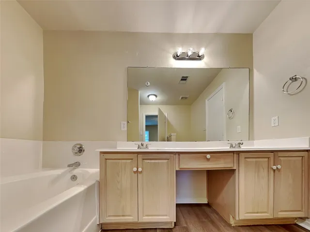 a bathroom with a double vanity sink a mirror and a bathtub