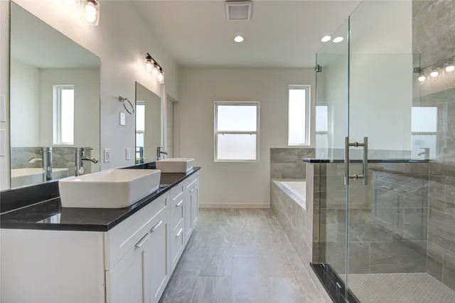 a bathroom with a granite countertop sink a large mirror and a bathtub