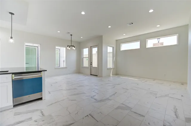 a view of an empty room with a kitchen and a window