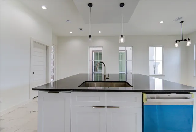 a kitchen with granite countertop a stove a sink and a refrigerator