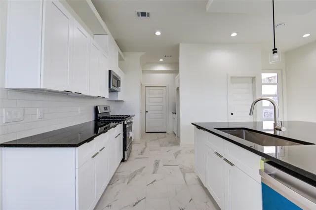 a kitchen with stainless steel appliances granite countertop a sink and a stove