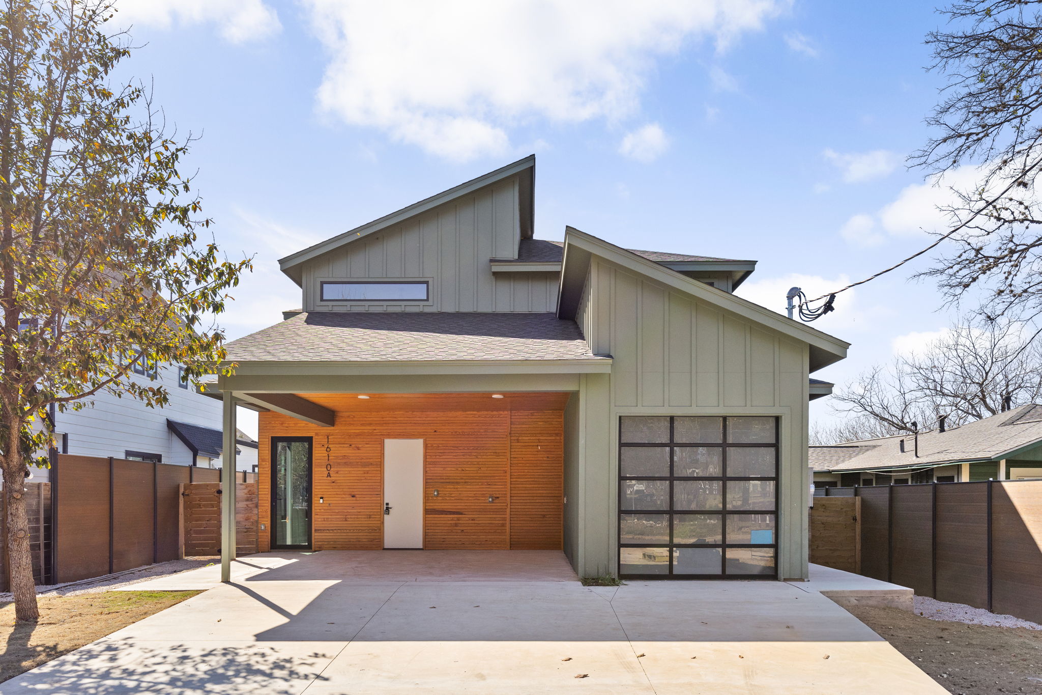 1610 Harvey Street, Unit 2 Austin, TX 78702 - Photo 36 of 38 Modern home featuring board and batten siding, roof with shingles, driveway, and a garage