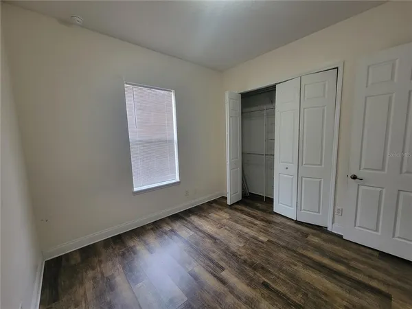a view of an empty room with closet and a window