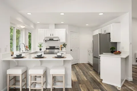 a kitchen with stainless steel appliances kitchen island granite countertop a sink and a refrigerator
