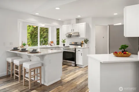 a kitchen with a sink stove cabinets and wooden floor