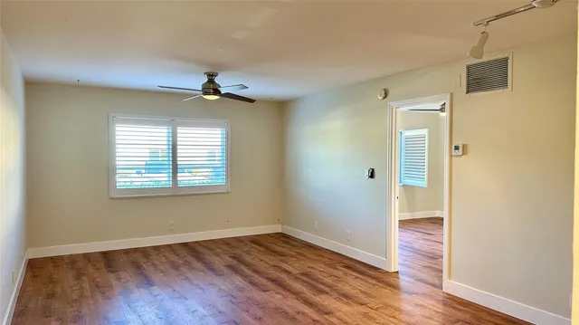 a view of an empty room with wooden floor and a window