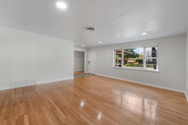 a view of empty room with wooden floor and fan