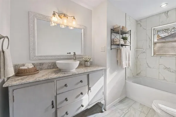 a bathroom with a granite countertop sink a mirror a bathtub and shower