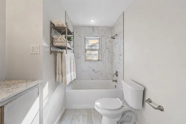 a bathroom with a granite countertop toilet a sink and bathtub
